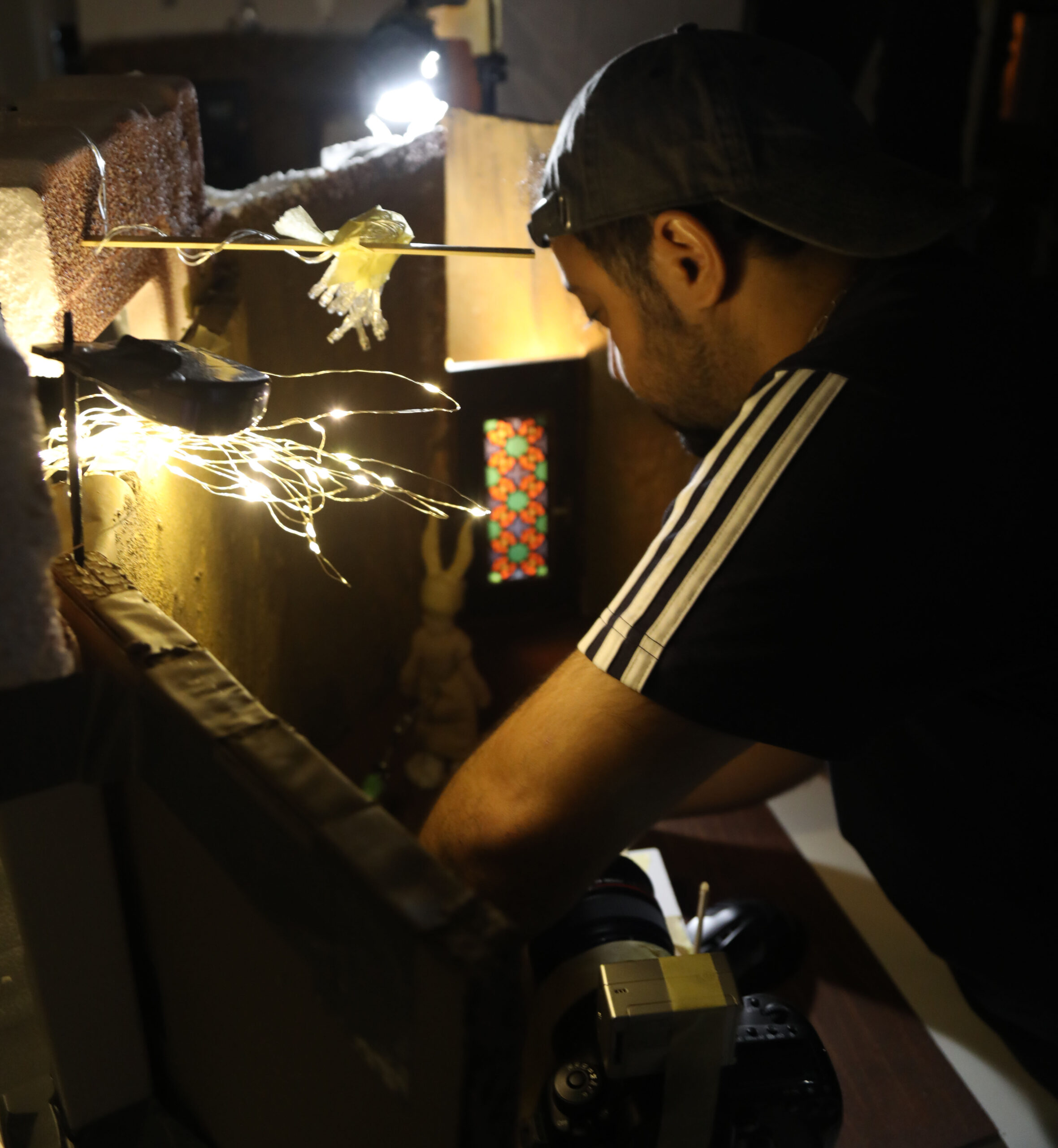 Der Direktor arbeitet am Miniatur Filmset und animiert eine Stop Motion Figur mit Menschenkörper und Hasenohren in einem Miniatur Wohnzimmer