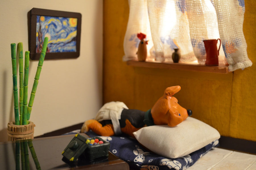 Figur eines braunen Hundes sitzt mit einer Windel auf einem Kissen in einem Wohnzimmer