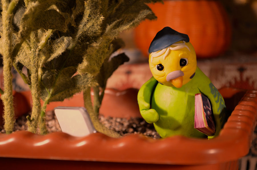Stop Motion Puppe eines weißen alten Wellensittichs sitzt in einem Blumentopf