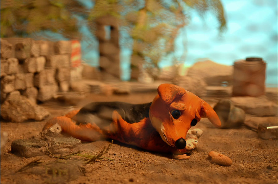 Stop Motion Puppe eines Hundes liegt auf der Straße eines Miniatur Filmsets