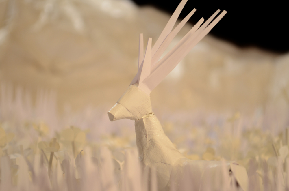Miniatur Hirsch aus Papier steht auf einer Wiese, die aus Papier für den Stop Motion Kurzfilm "Kitchen Dreams" gestaltet wurde